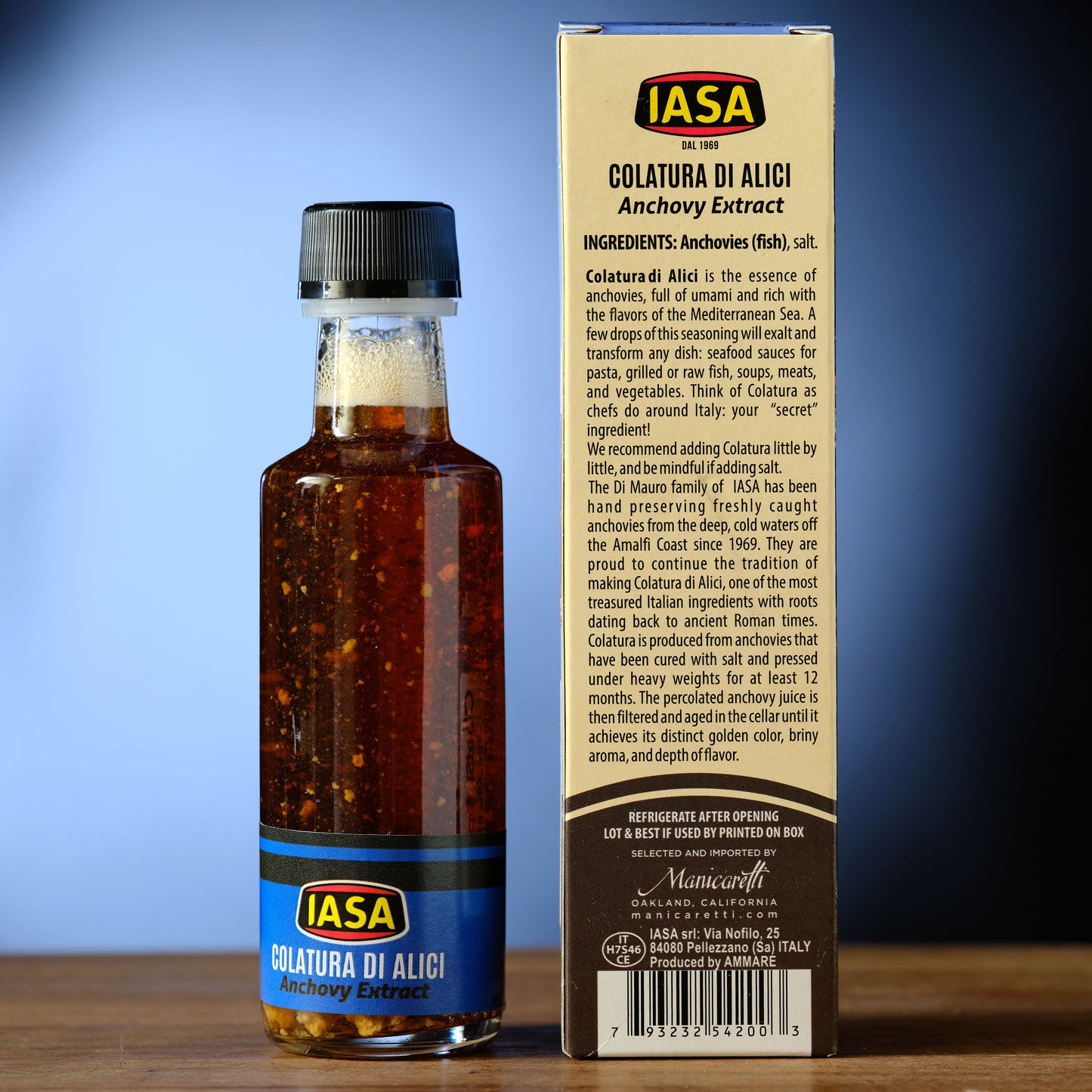 Bottle of IASA Colatura di Alici anchovy extract with its packaging on a wooden surface A Fishy Elixir - Anchovy Syrup