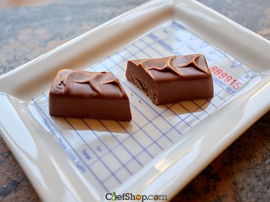 Two pieces of chocolate on a white tray with a grid background Ara Chocolat Sesame Praline Bar