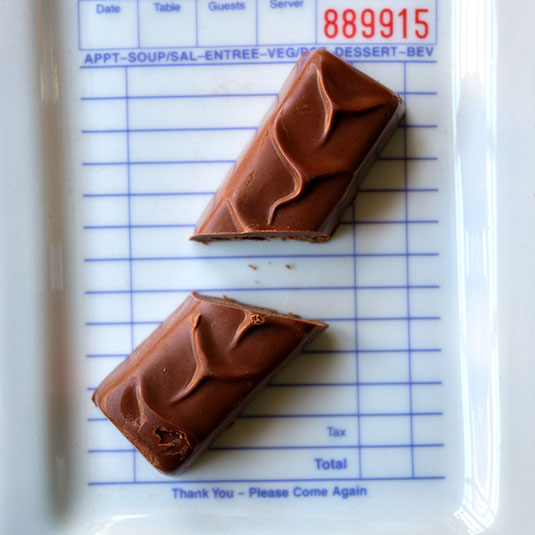Two chocolate bars on a restaurant receipt with a visible order number Ara Chocolat Hazelnut Praline Bar