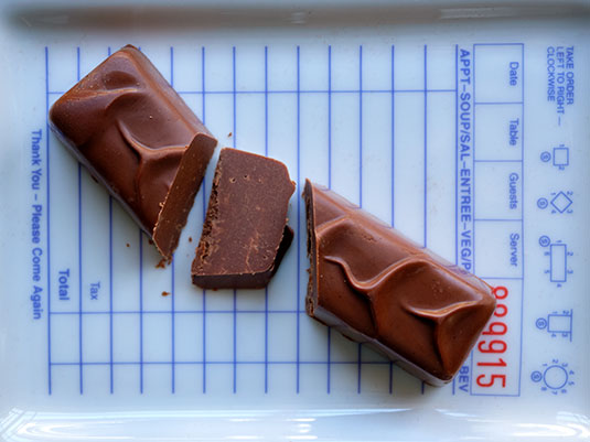 Ara Chocolat Almond Praline Bar Chocolate bar cut into pieces on a printed surface