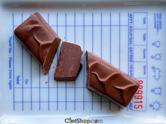 Ara Chocolat Almond Praline Bar Chocolate bar cut into pieces on a printed surface