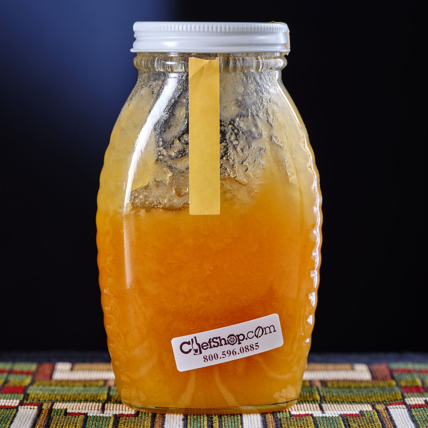 Jar of honey with a label on a colorful fabric background back of jar