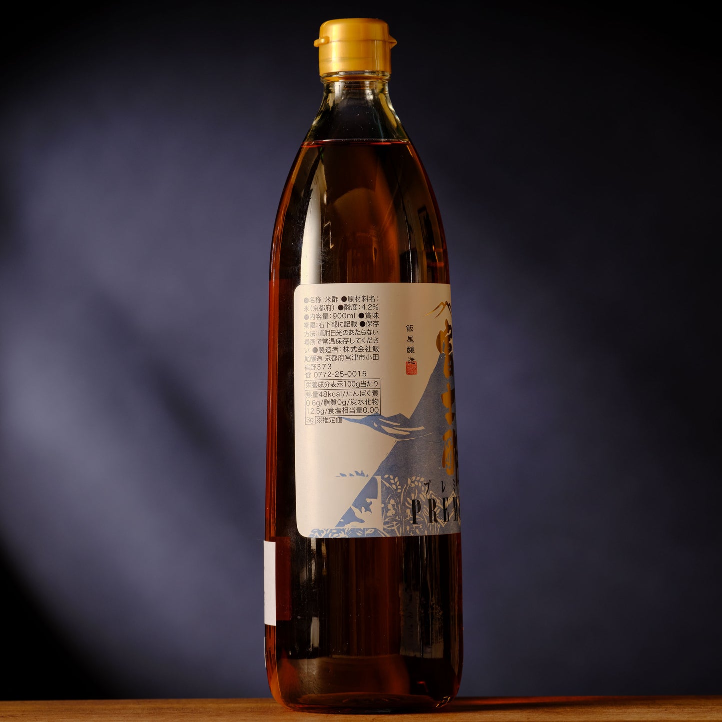 Bottle of syrup with a label on a dark background Iio Jozo Pure PREMIUM Rice Vinegar - 900 ml