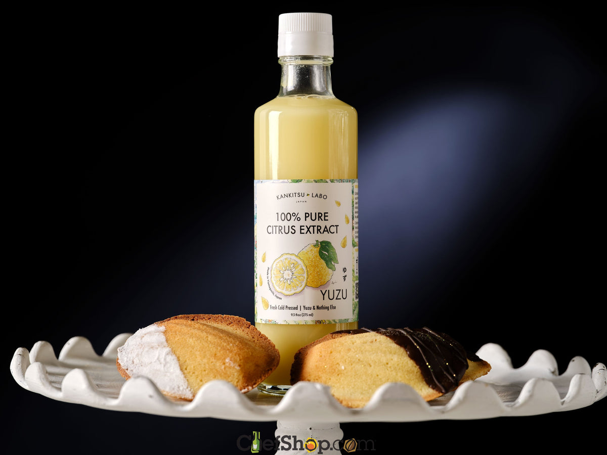 Bottle of Kankitsu Labo Citrus Extract 100% pure citrus extract with a lemon label on a white cake stand against a black background with cookies