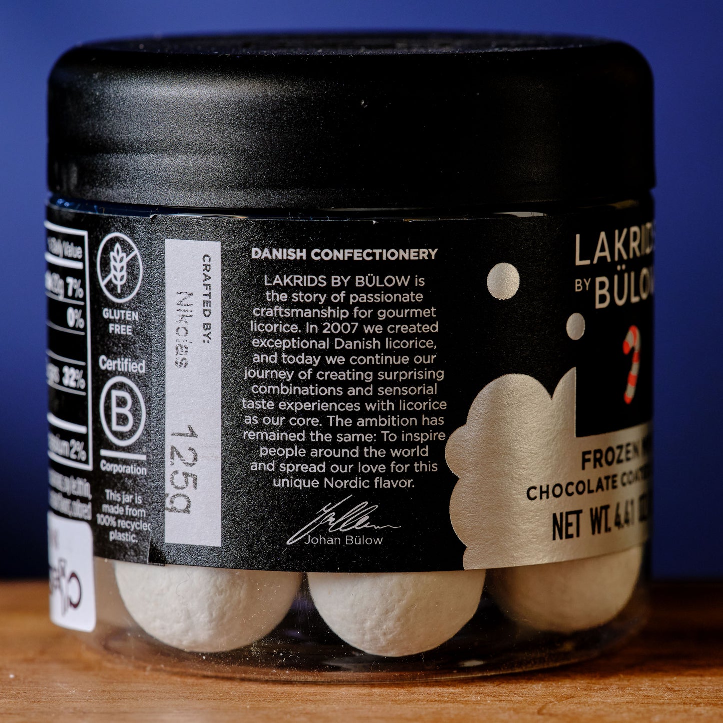 Jar of Lakrids by Bülow chocolate candy with a black lid on a wooden surface. Lakrids Frozen Mint Chocolate Coated Licorice About