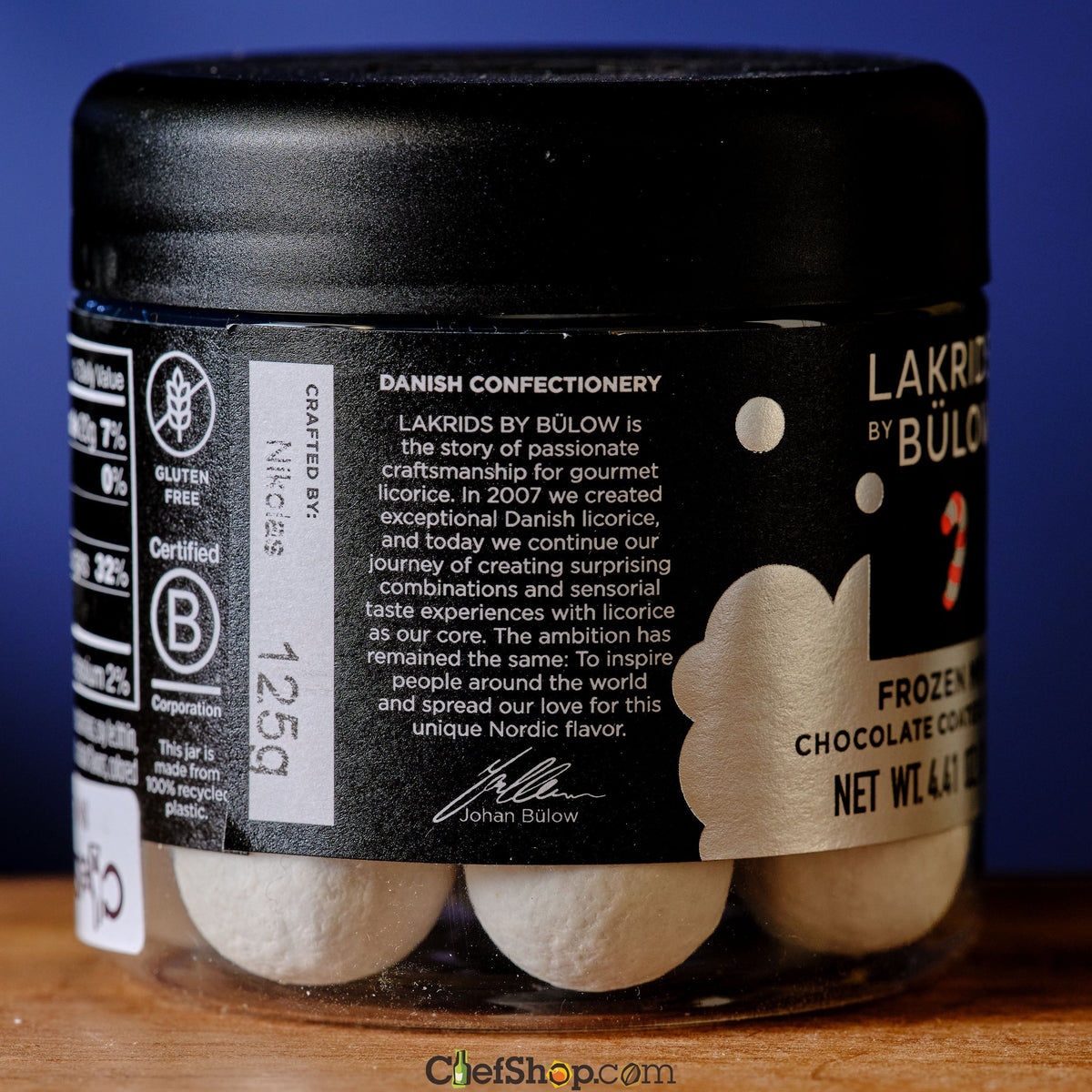 Jar of Lakrids by Bülow chocolate candy with a black lid on a wooden surface. Lakrids Frozen Mint Chocolate Coated Licorice About