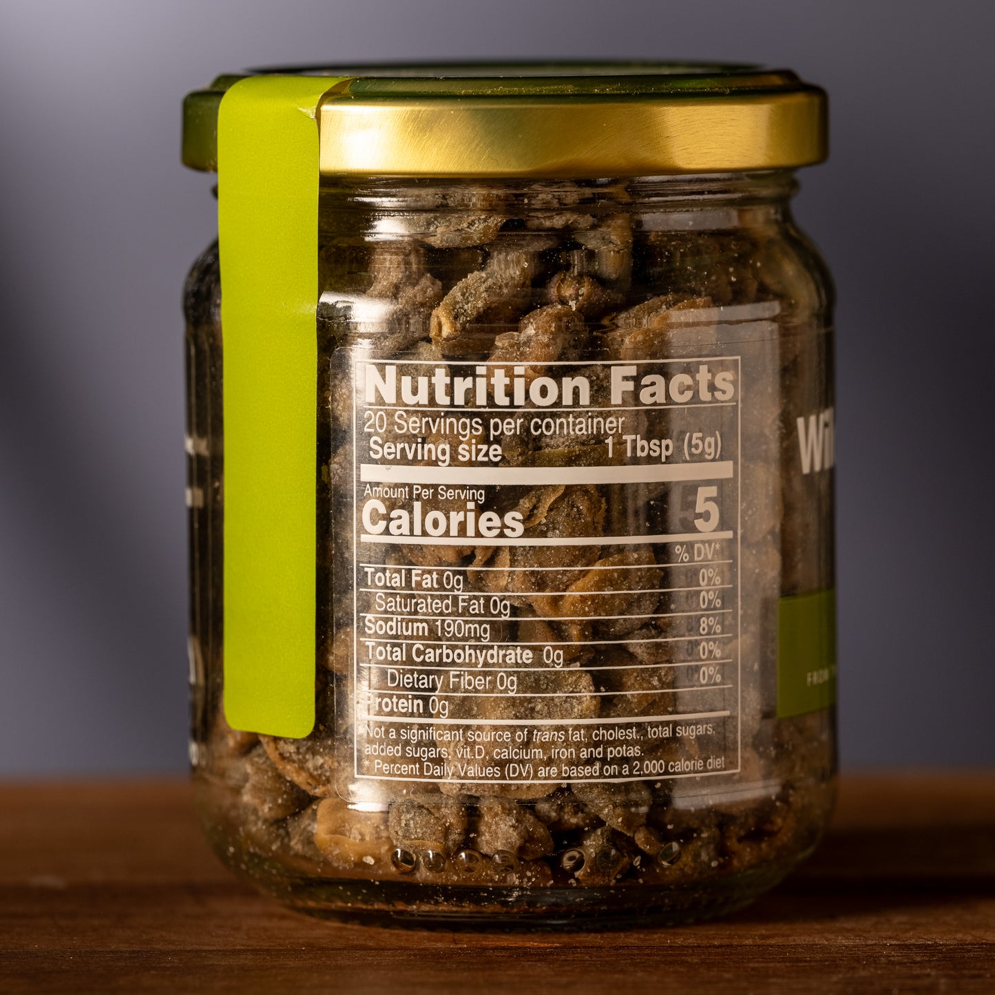 Jar of capers with a nutrition facts label on a wooden surface