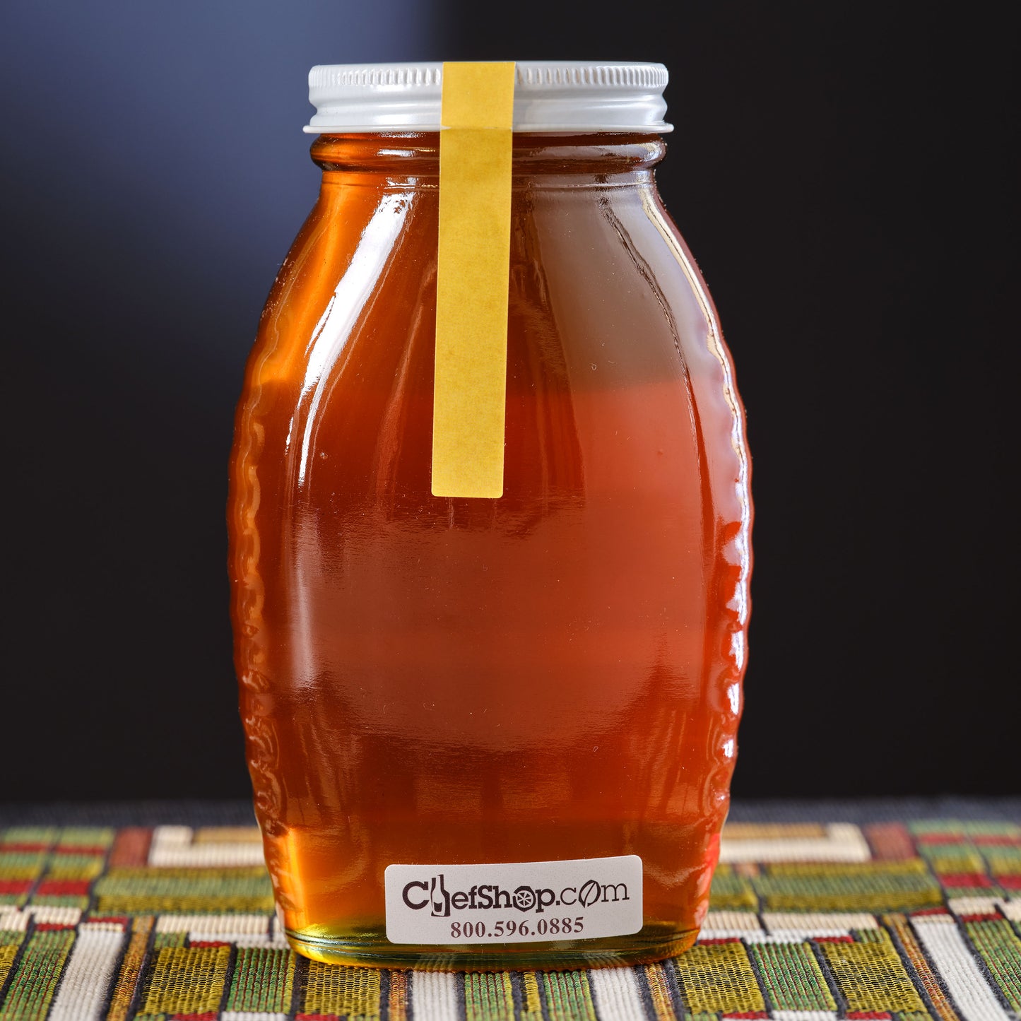 Jar of honey Meadowfoam on a colorful mat against a dark background