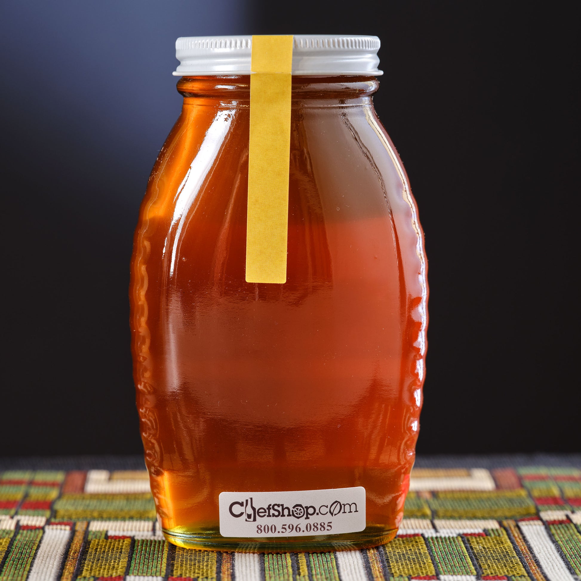 Jar of honey Meadowfoam on a colorful mat against a dark background