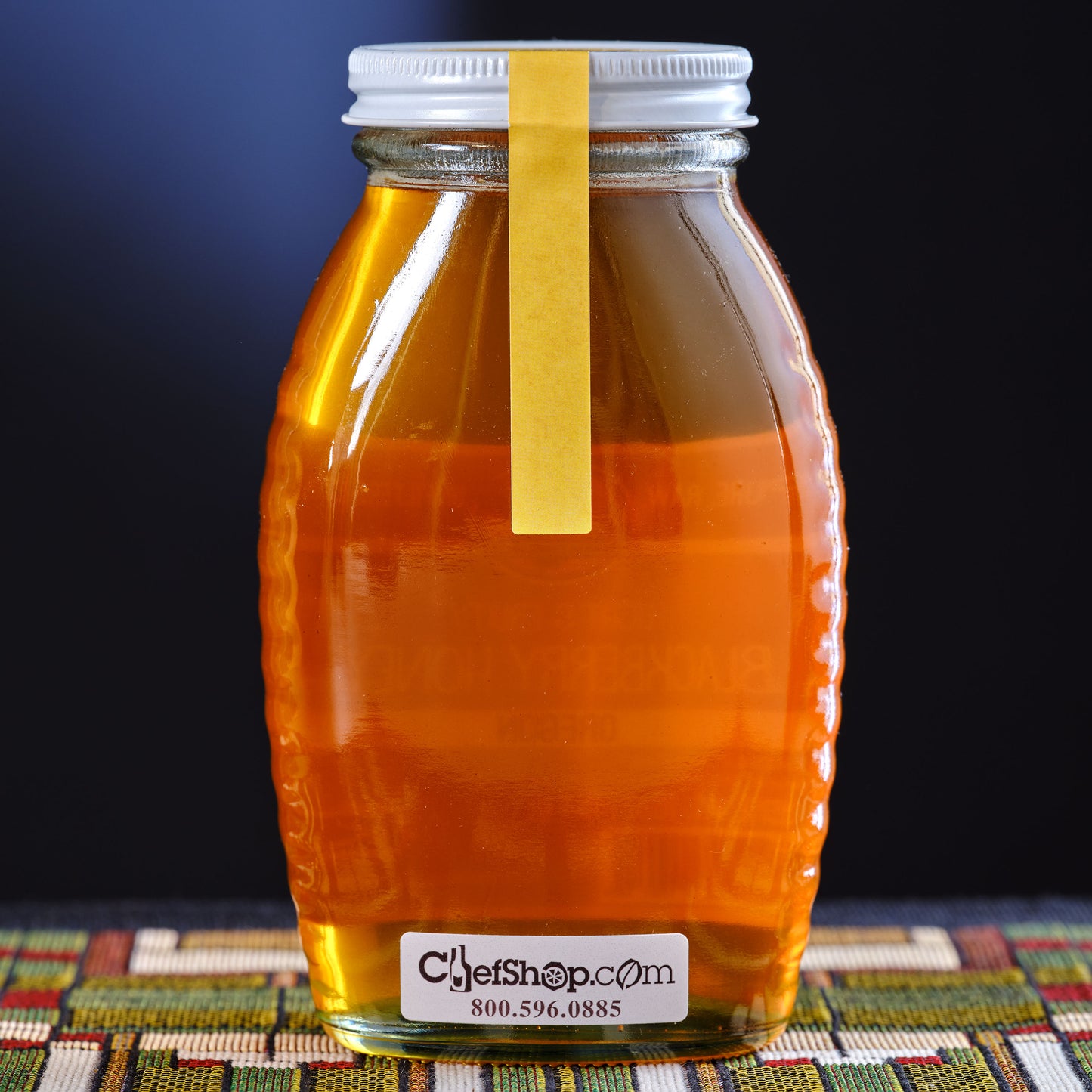 Jar of mint honey on a colorful mat against a dark background