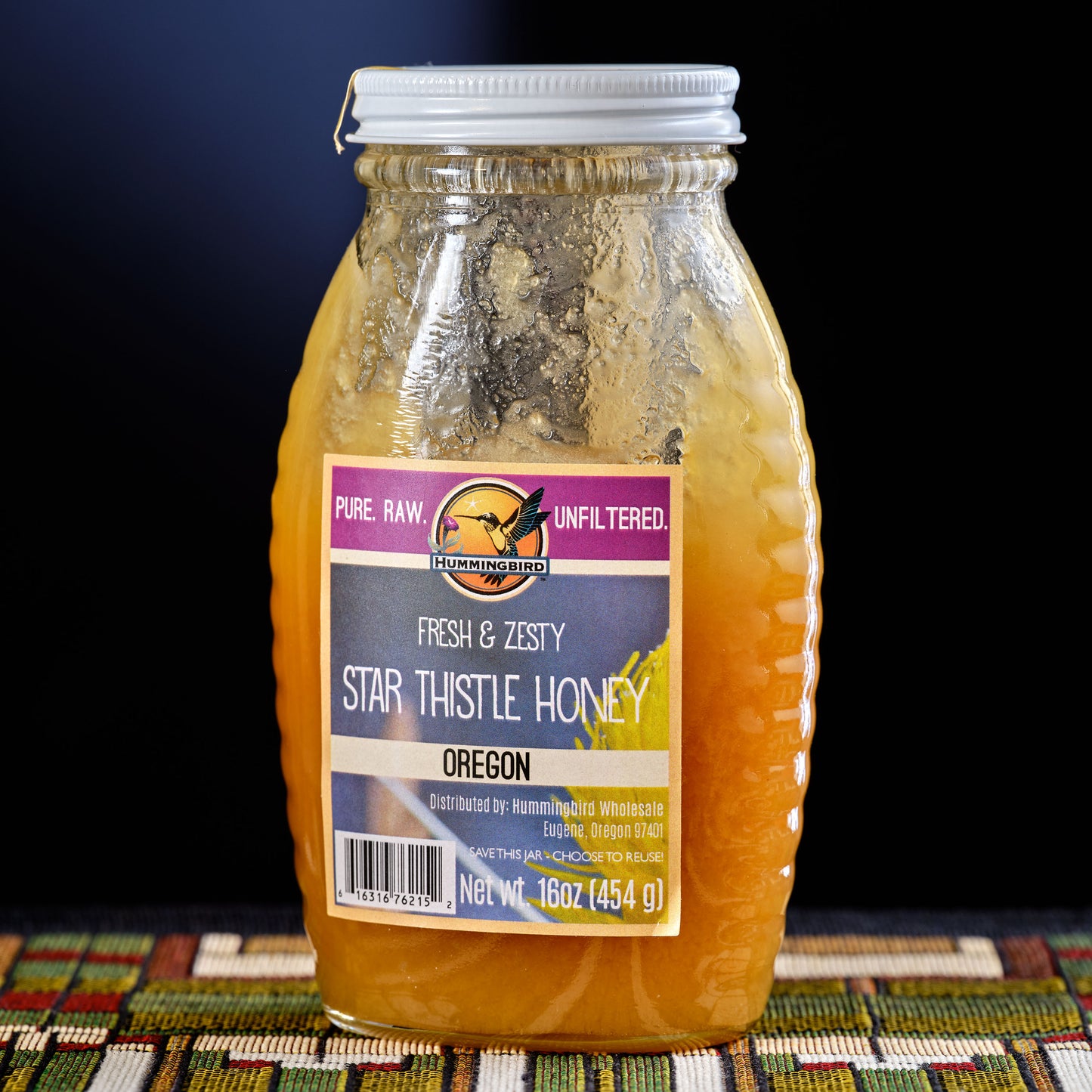 Jar of star thistle honey with a label on a dark background