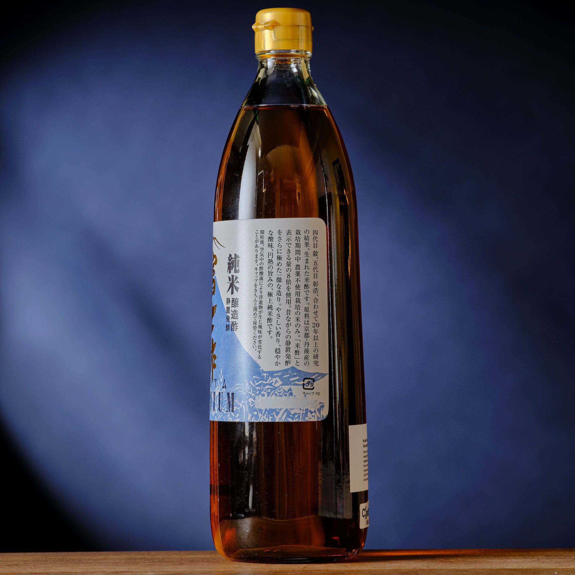 Bottle of Japanese sake with a blue label on a wooden surface and blue background