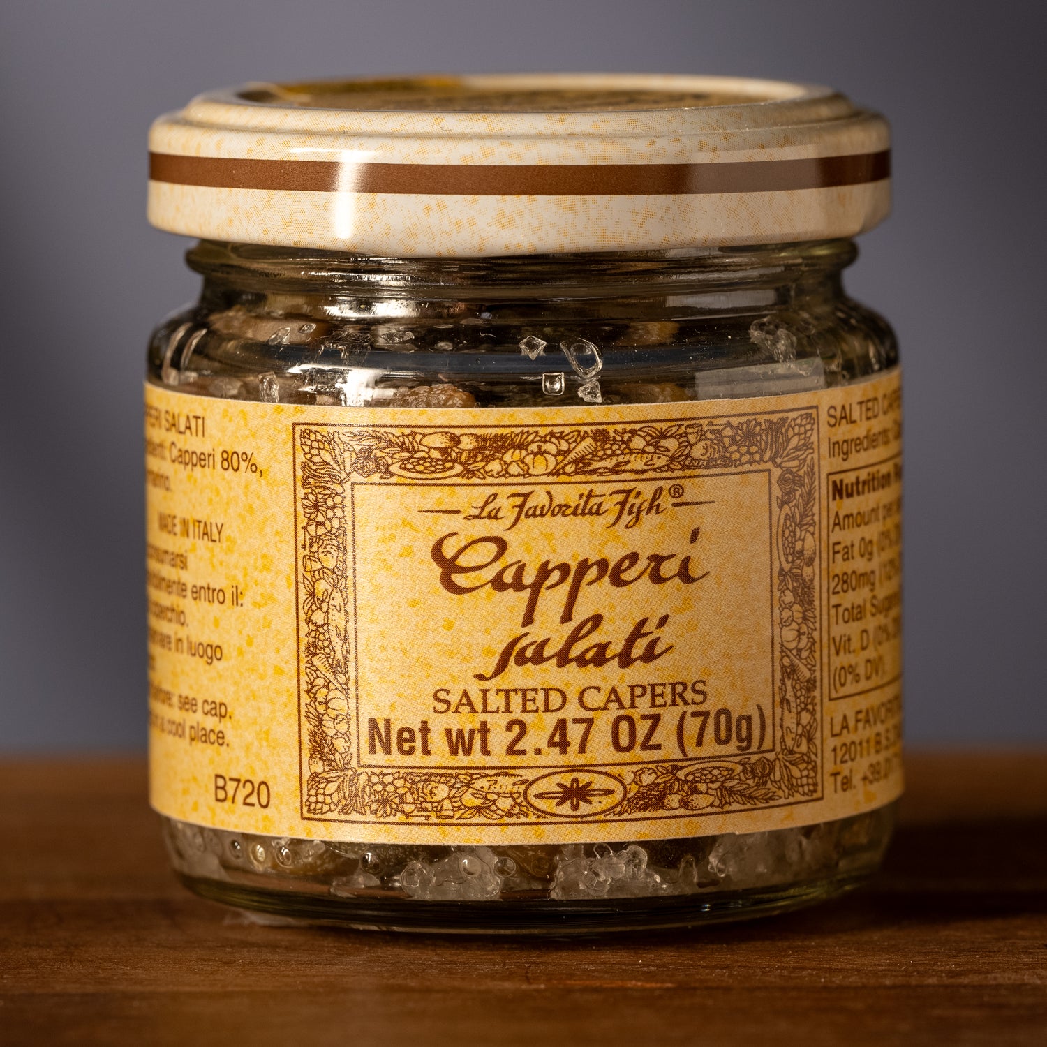 Jar of La Favella Fish Capperi Salati salted capers on a wooden surface with a gray background