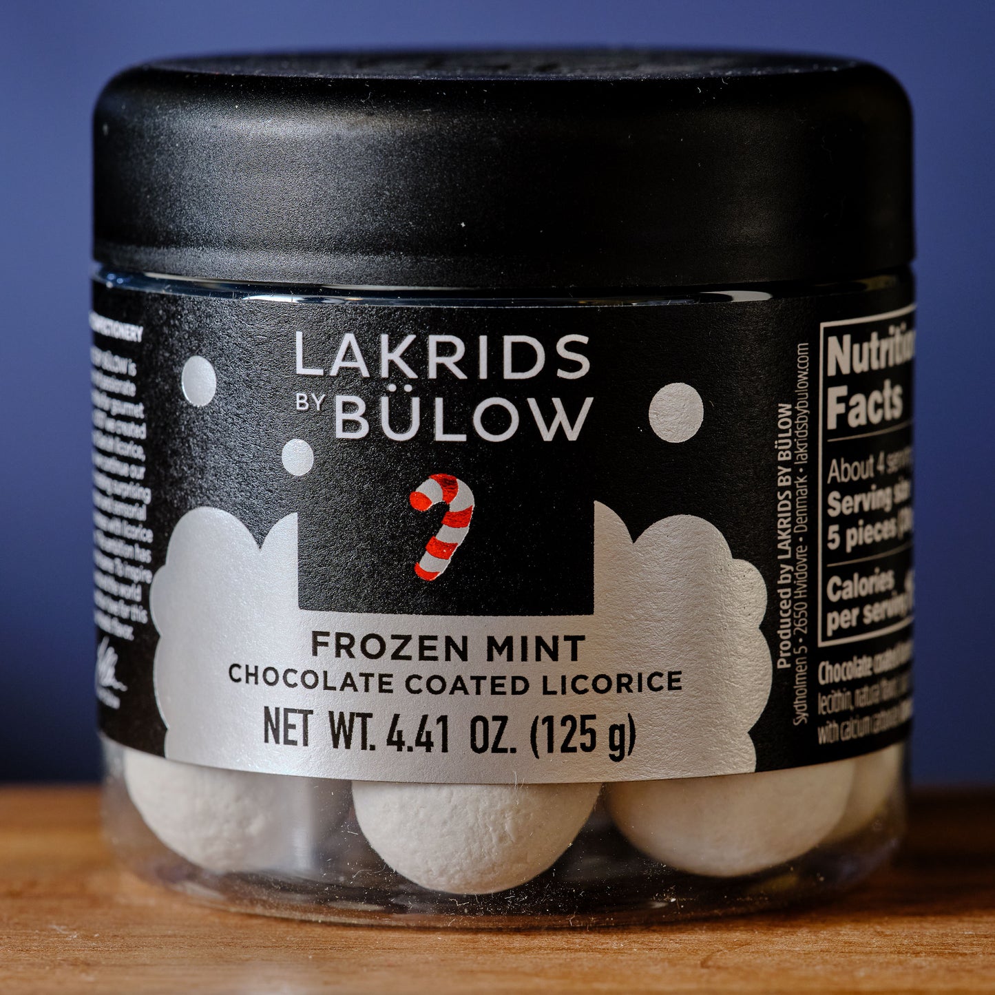 Jar of Lakrids by Bulow Frozen Mint chocolate coated licorice on a wooden surface with a blue background