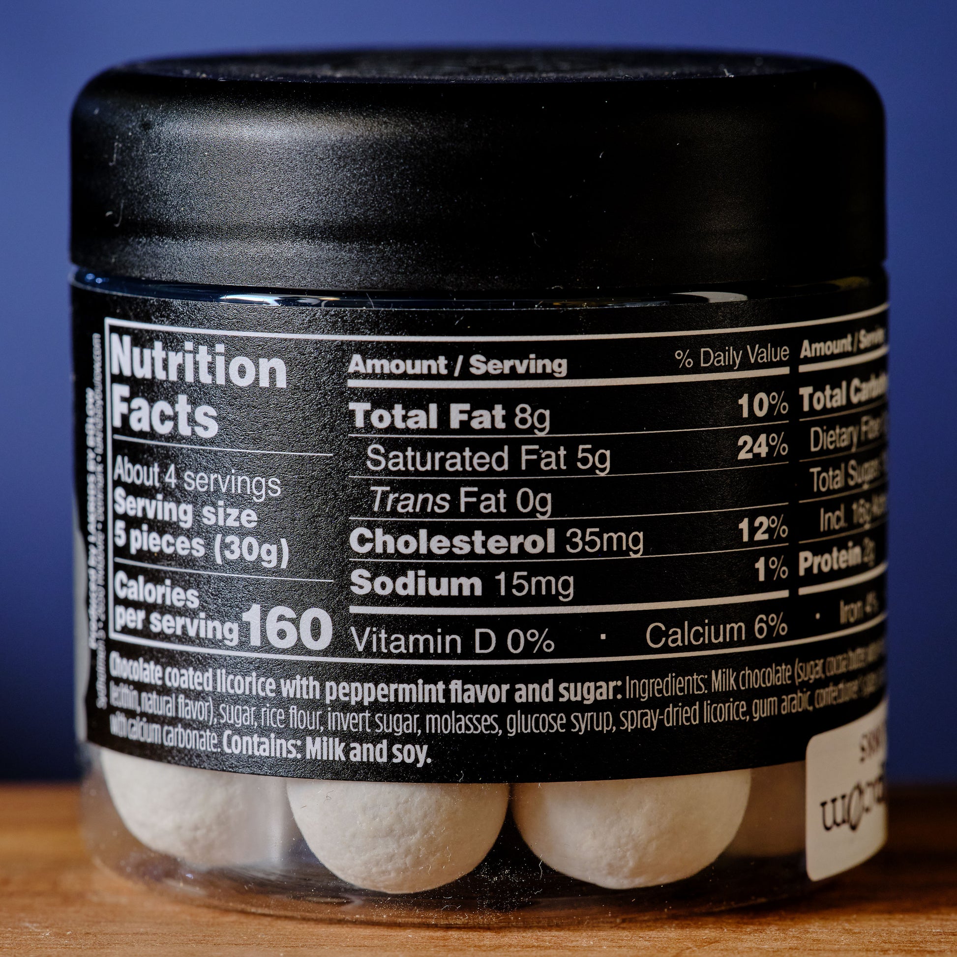 Jar of chocolate-coated licorice with nutrition label on a wooden surface Lakrids Frozen Mint Chocolate Coated Licorice