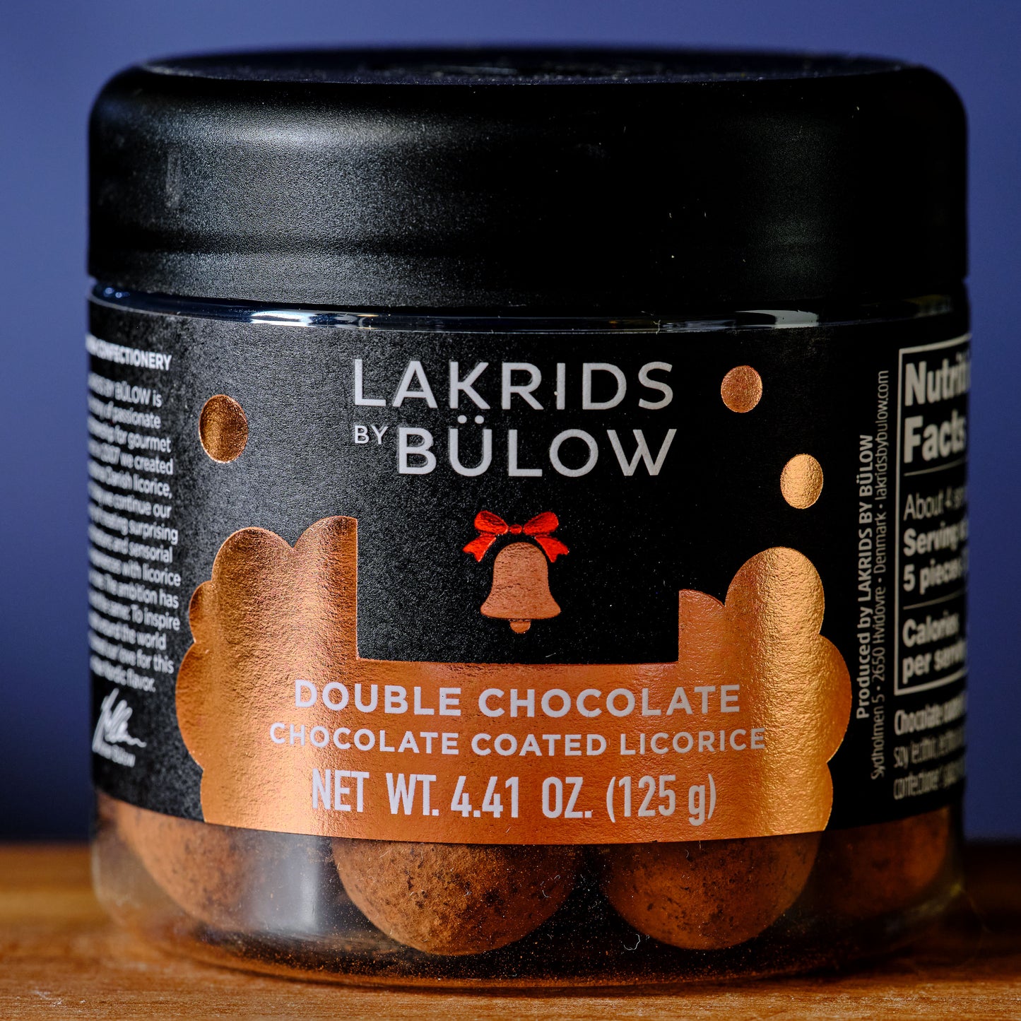 Jar of Lakrids by Bölow Double Chocolate Chocolate Coated Licorice on a wooden surface with a blue background