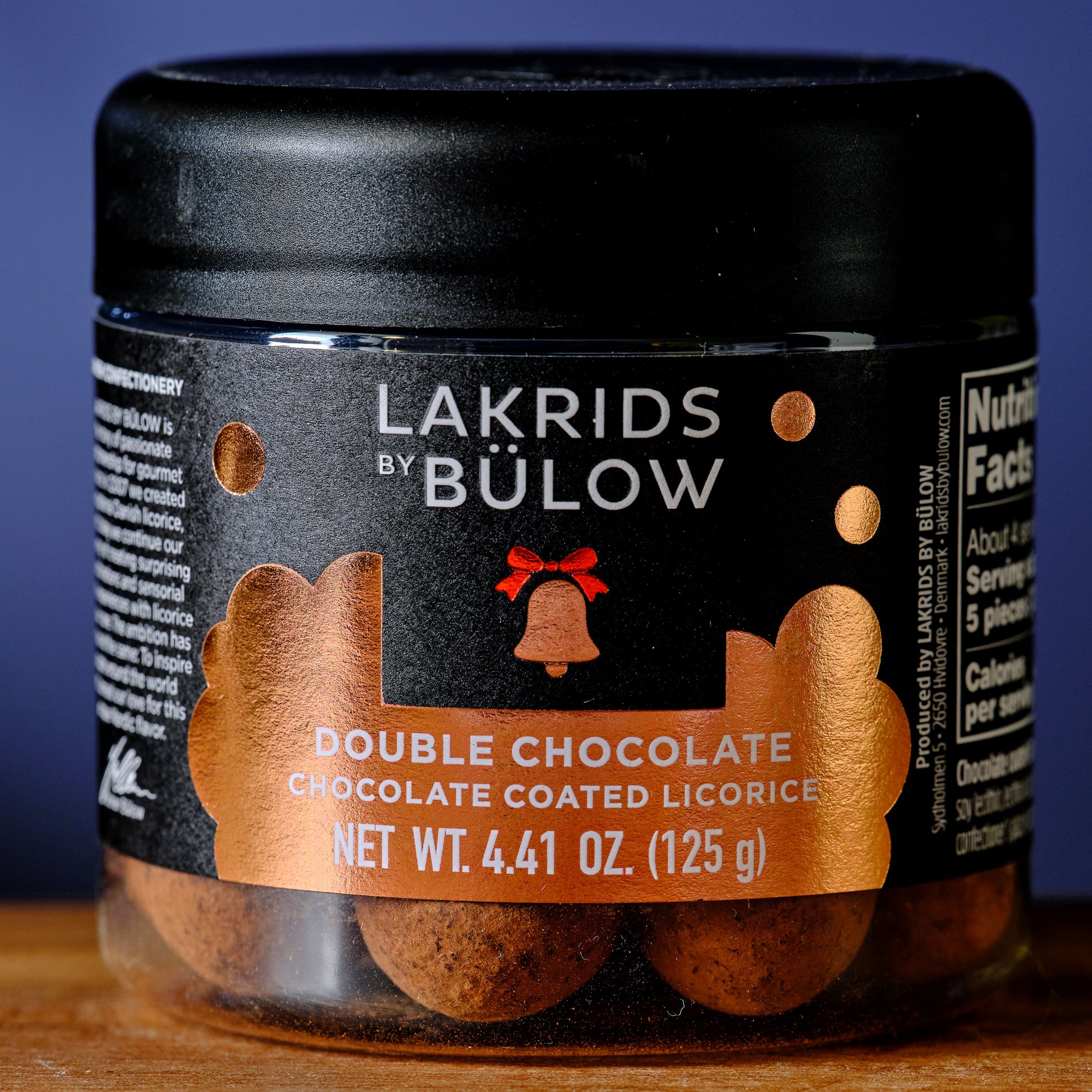 Jar of Lakrids by Bölow Double Chocolate Chocolate Coated Licorice on a wooden surface with a blue background