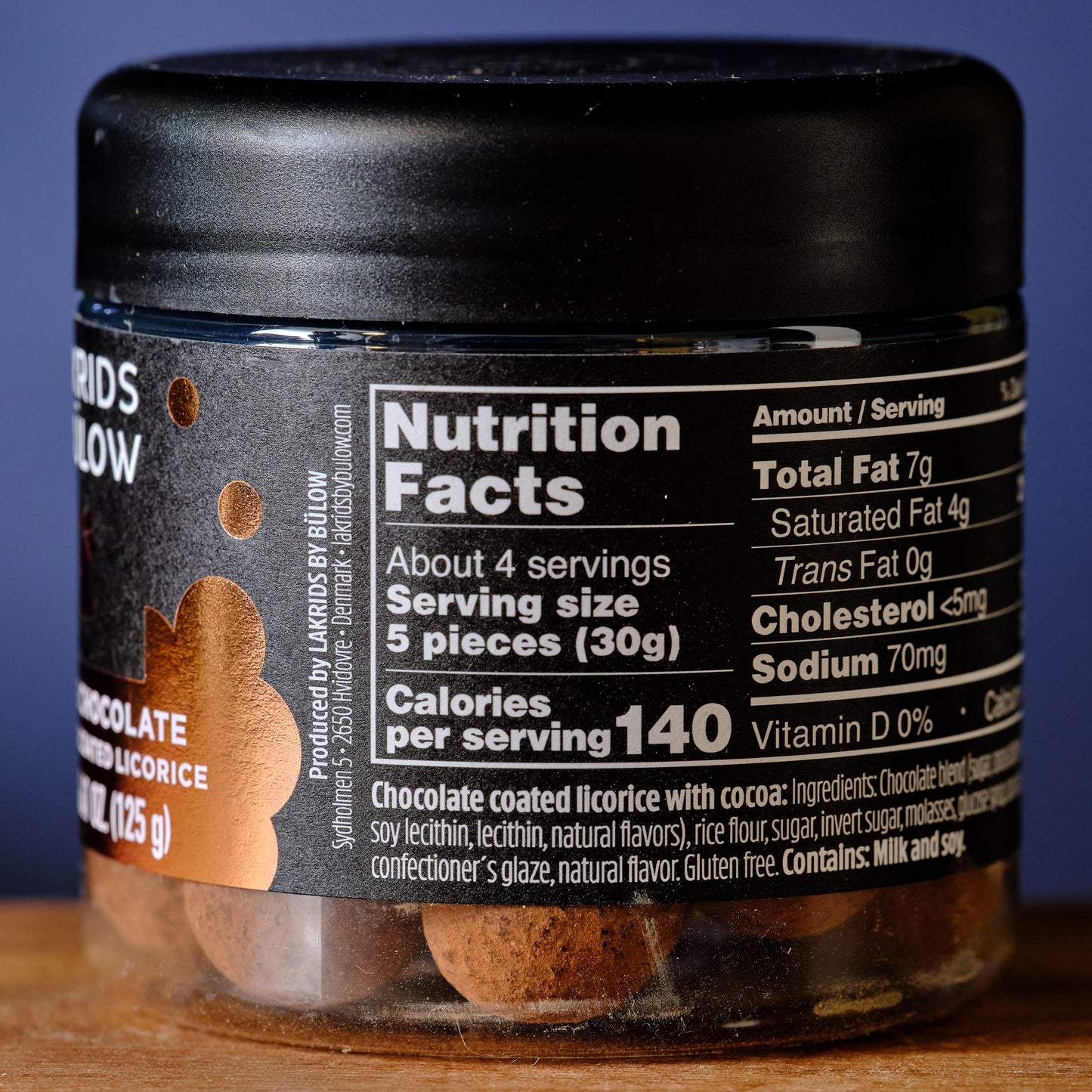 Jar of chocolate coated licorice with nutrition facts label on a wooden surface