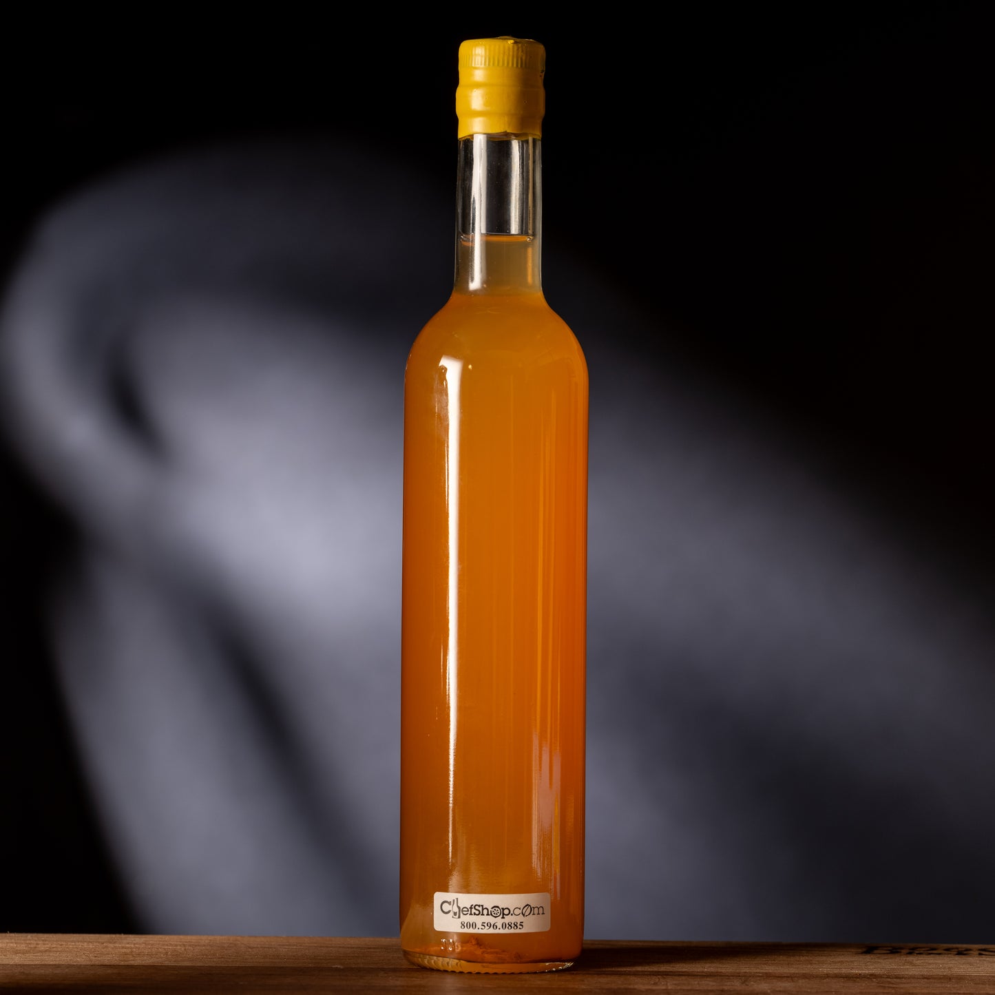 Bottle of orange liquid with a yellow cap on a dark background