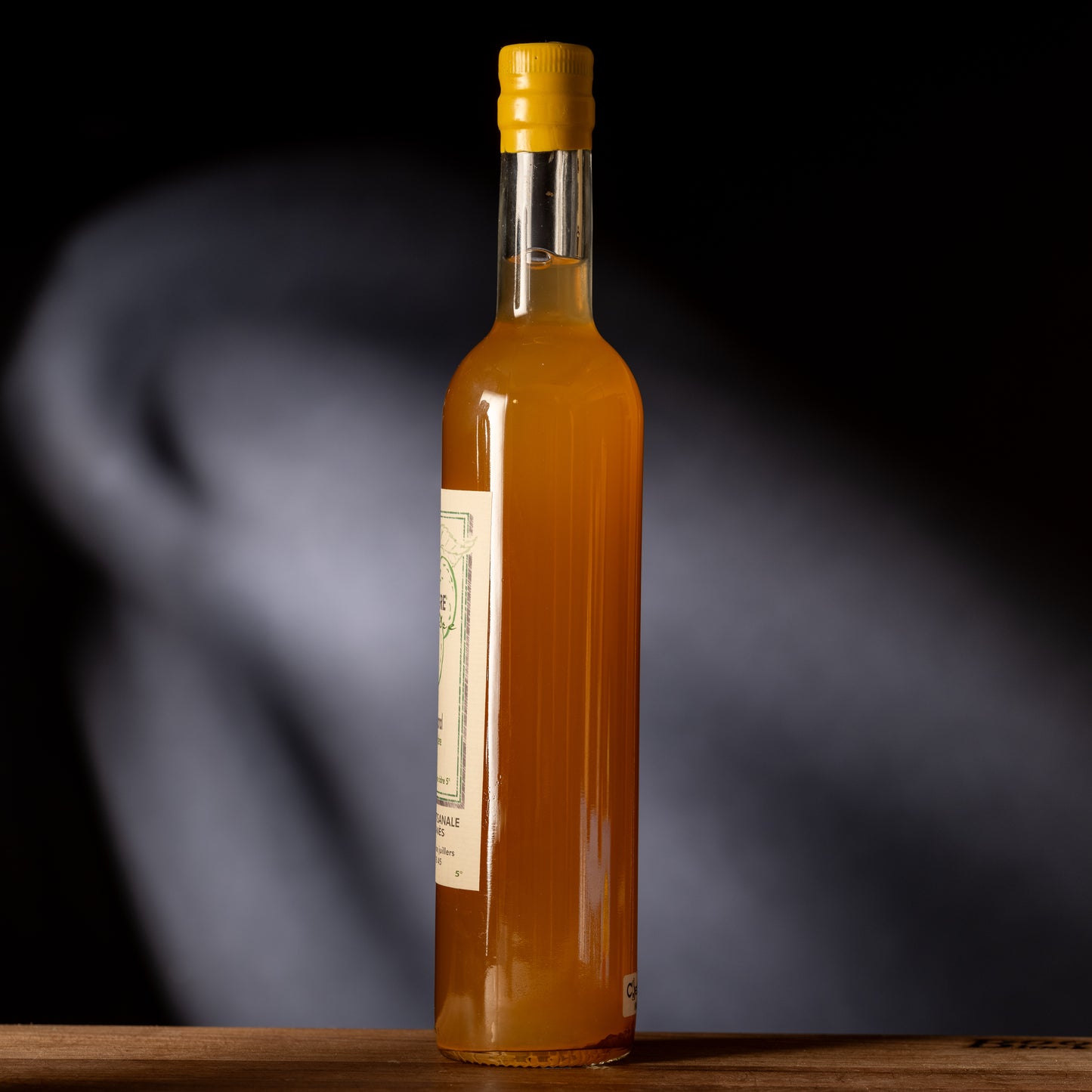 Bottle of orange liquid with a yellow cap on a dark background