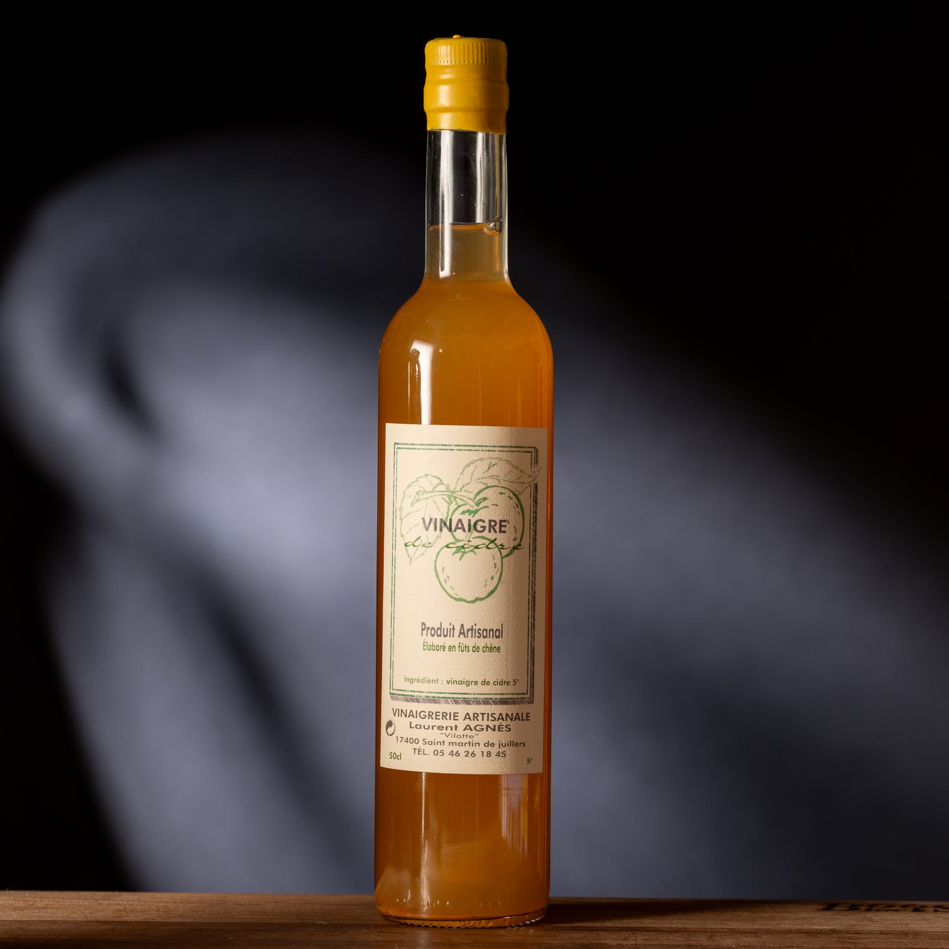 Bottle of orange liquid vinegar with a label on a dark background