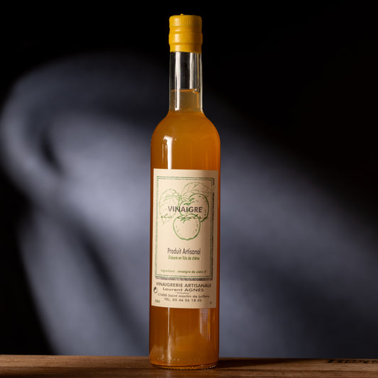 Bottle of orange liquid vinegar with a label on a dark background