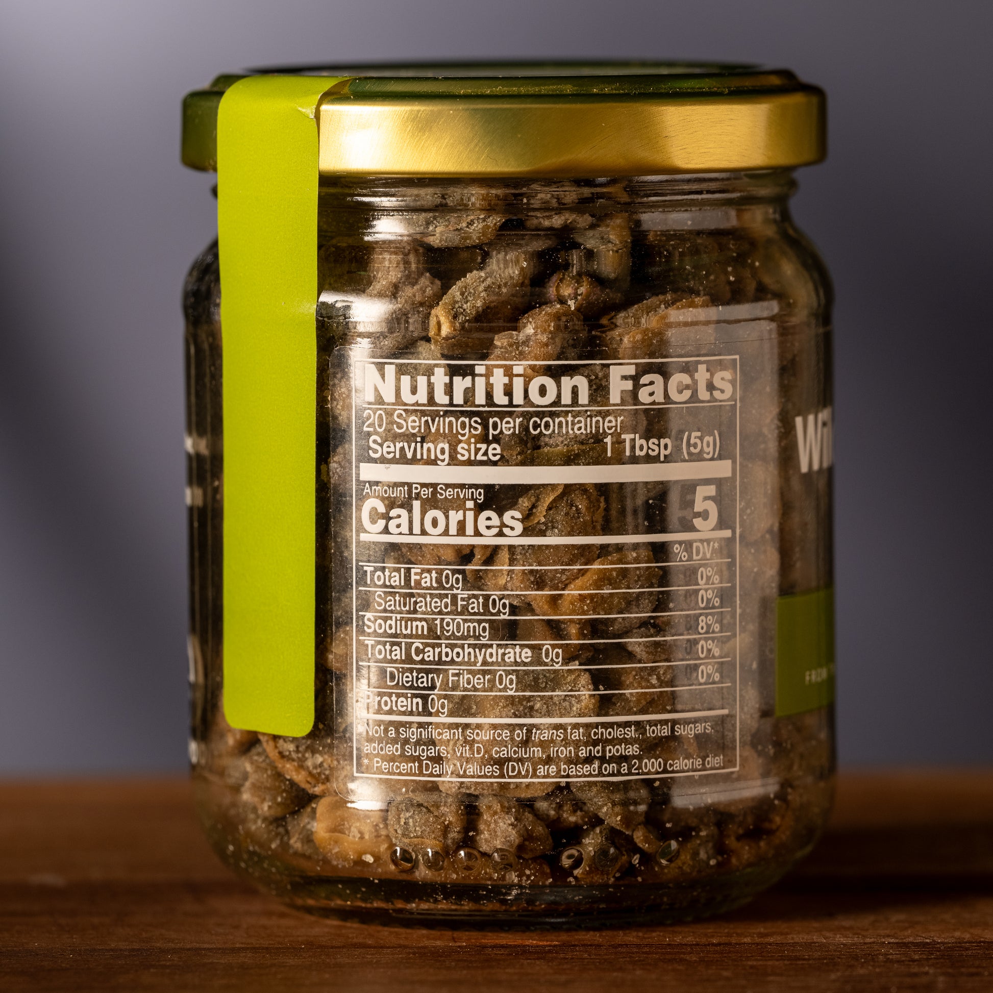 Jar of capers with a nutrition facts label on a wooden surface