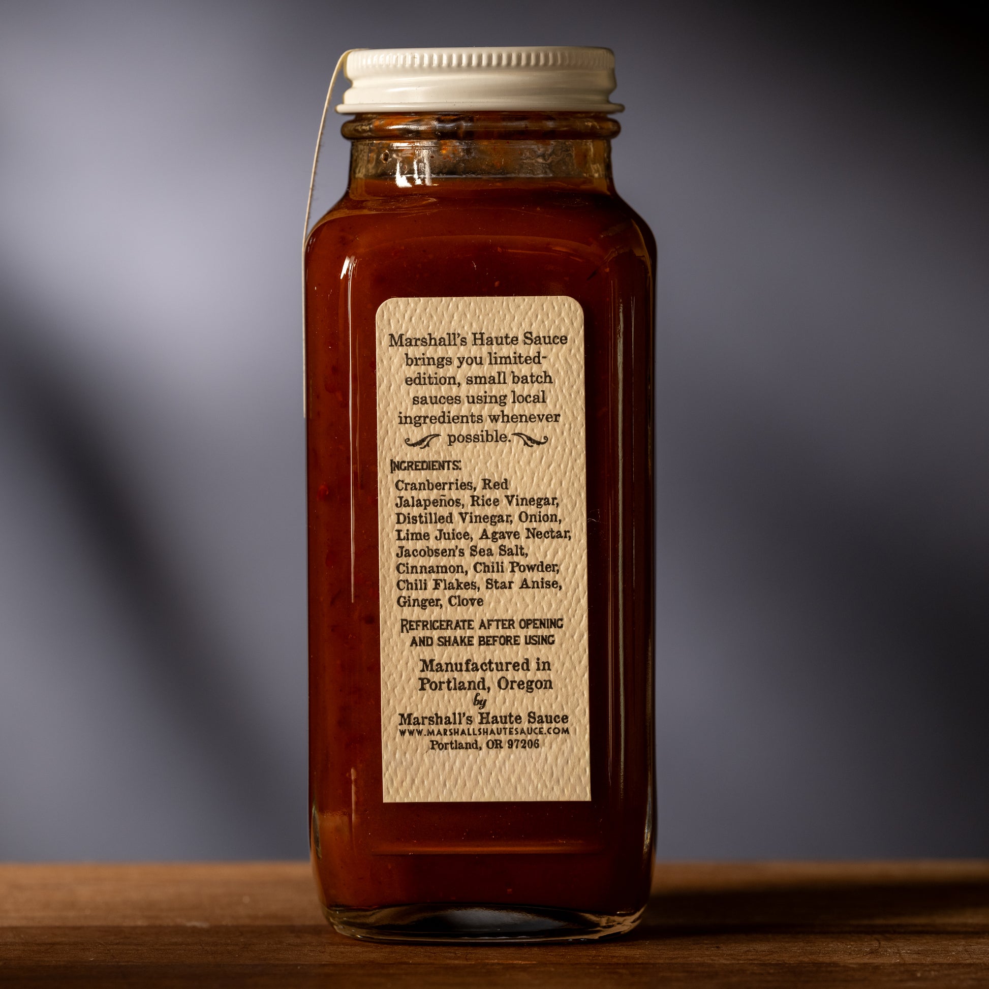 Jar of Marshall's Haute Sauce with a label on a wooden surface and gray background