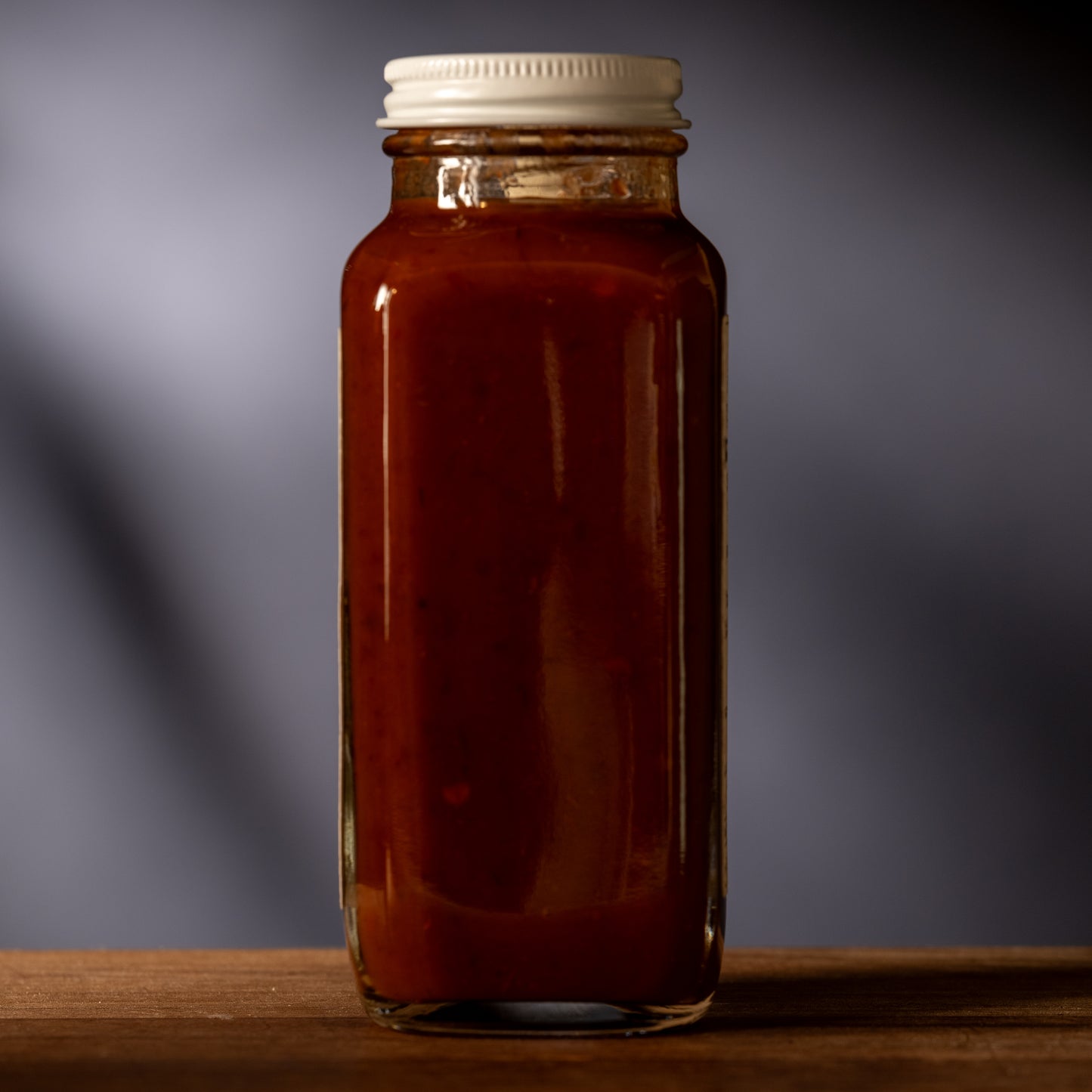 Glass jar with a white lid on a wooden surface against a dark background