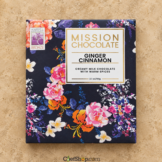 A square box of Mission Chocolate Ginger Cinnamon, featuring a dark navy floral pattern with pink, orange, and white flowers, set against a textured beige background.