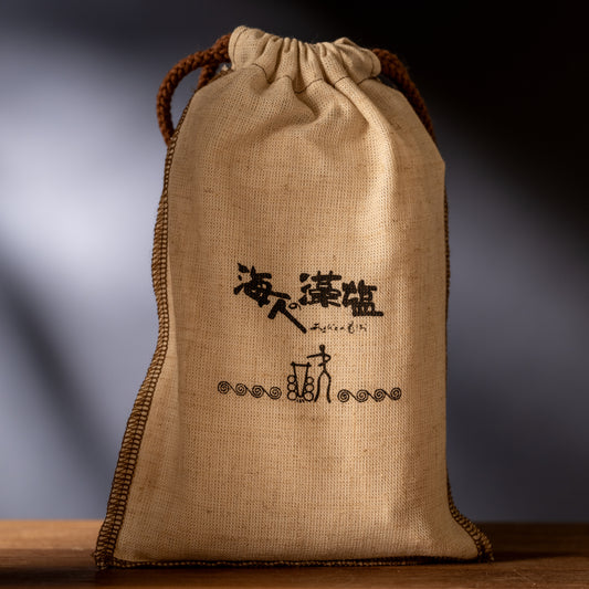 Burlap bag with Japanese writing on it sitting on wood