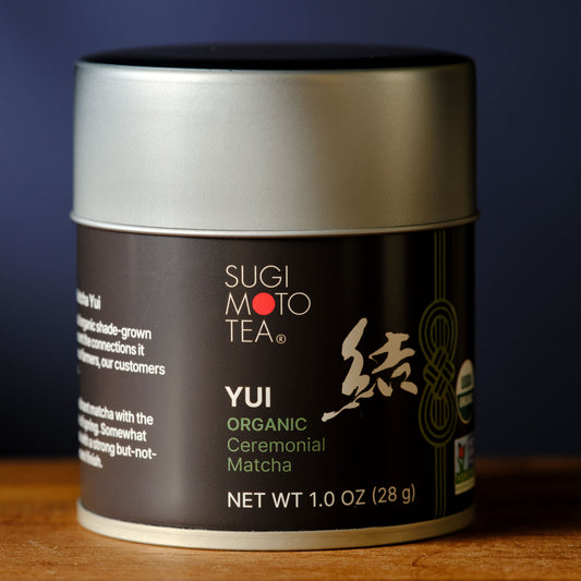 Sugimoto Tea Yui Organic Ceremonial Matcha container on a wooden surface with a dark background