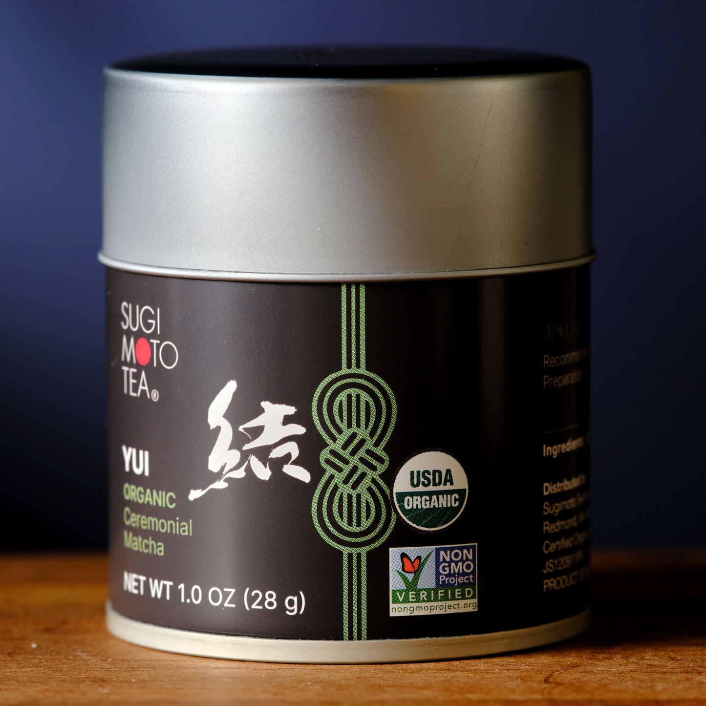 Sugimoto Tea Yui Organic Ceremonial Matcha container on a wooden surface with a dark background