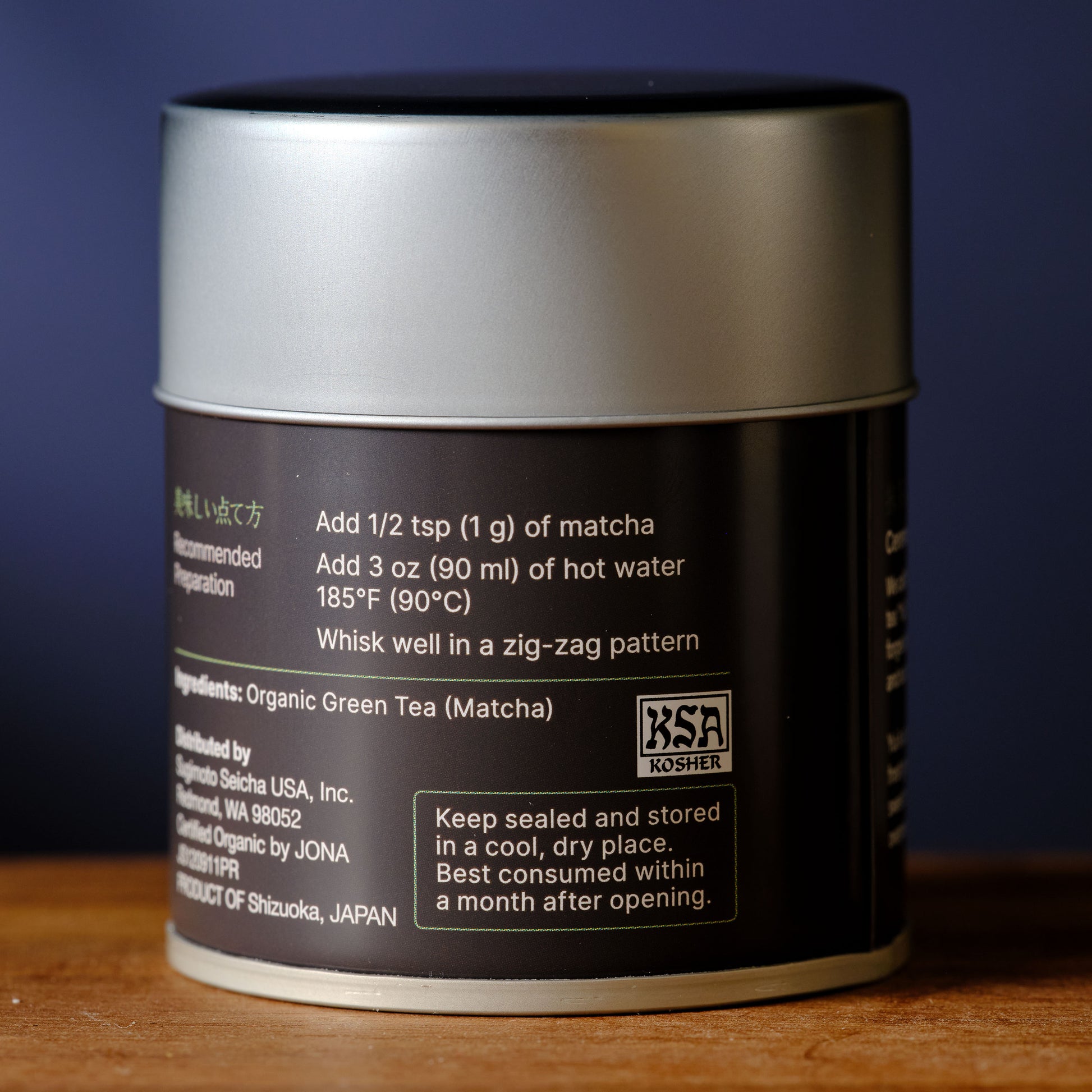 Matcha green tea canister with label on a wooden surface and dark background